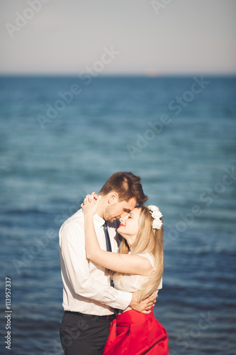 Young happy couple walking on beach smiling holding around each other. Love story © olegparylyak