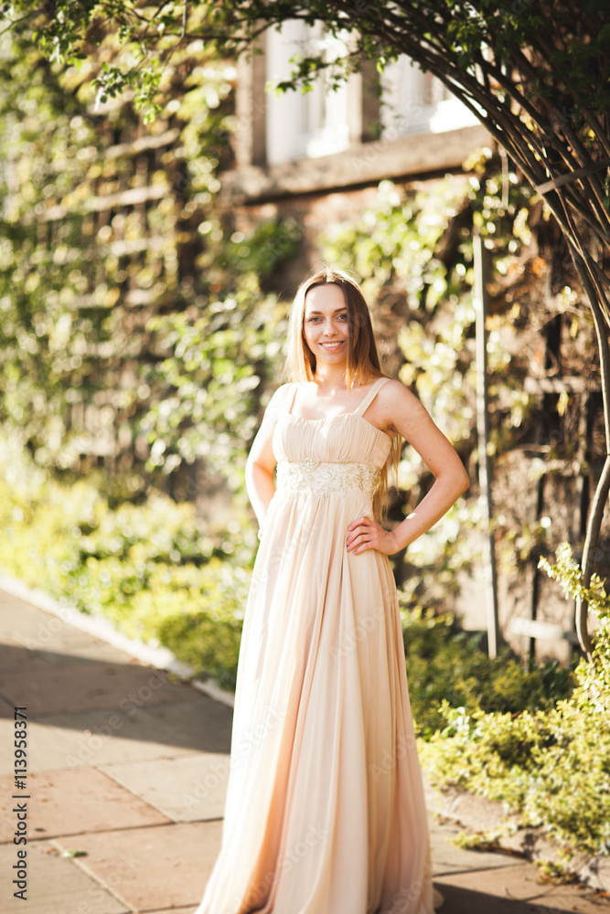 Attractive young woman with long dress enjoying her time outside in park sunset background Attractive young woman with long dress enjoying her time outside in park sunset background