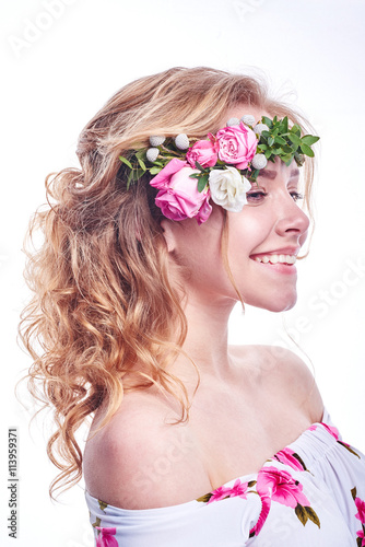 Beauty girl takes beautiful flowers in her hands. Blowing flower. Hairstyle with flowers. Fantasy girl portrait in pastel colors. Summer fairy portrait. Long permed hair.