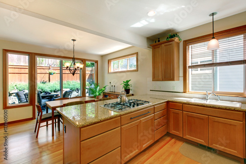 Brown and white kitchen room with hardwood floor  cabinets and eating area.