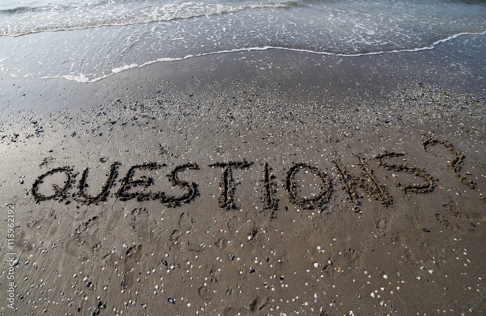Fototapeta premium Questions with question mark written in large letters on the san