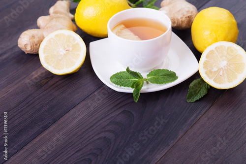 Cup of tea with lemon and other ingridients on a dark wooden background