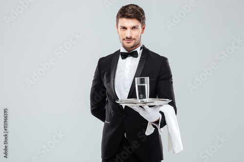 Butler in gloves holding glass of water on silver tray