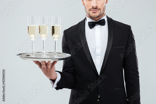 Waiter in tuxedo holding tray with glasses of champagne