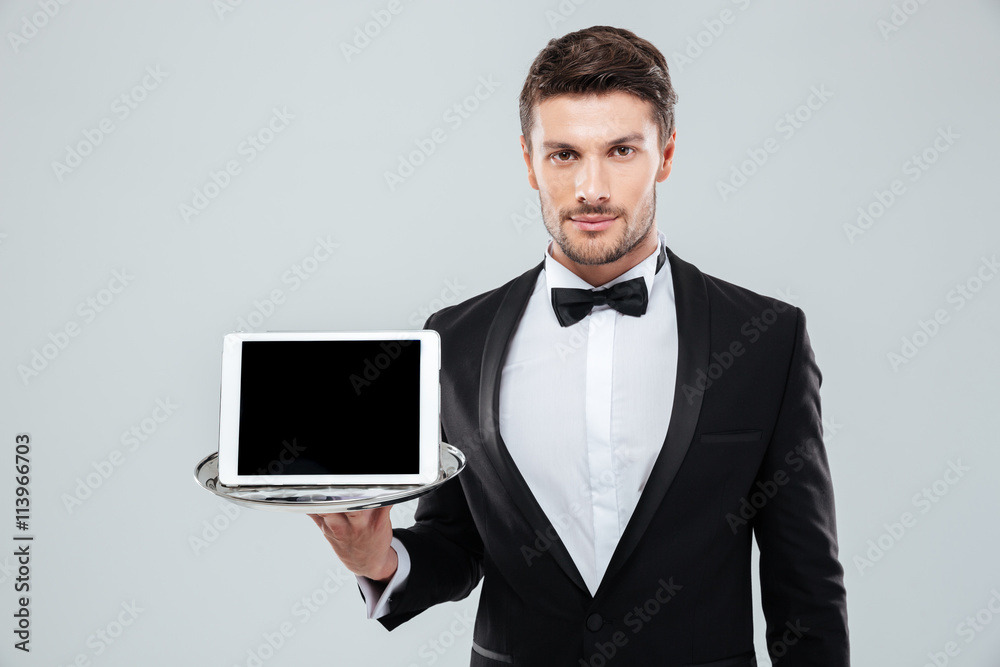 Butler in tuxedo holding blank screen tablet on tray Butler in tuxedo holding blank screen tablet on tray