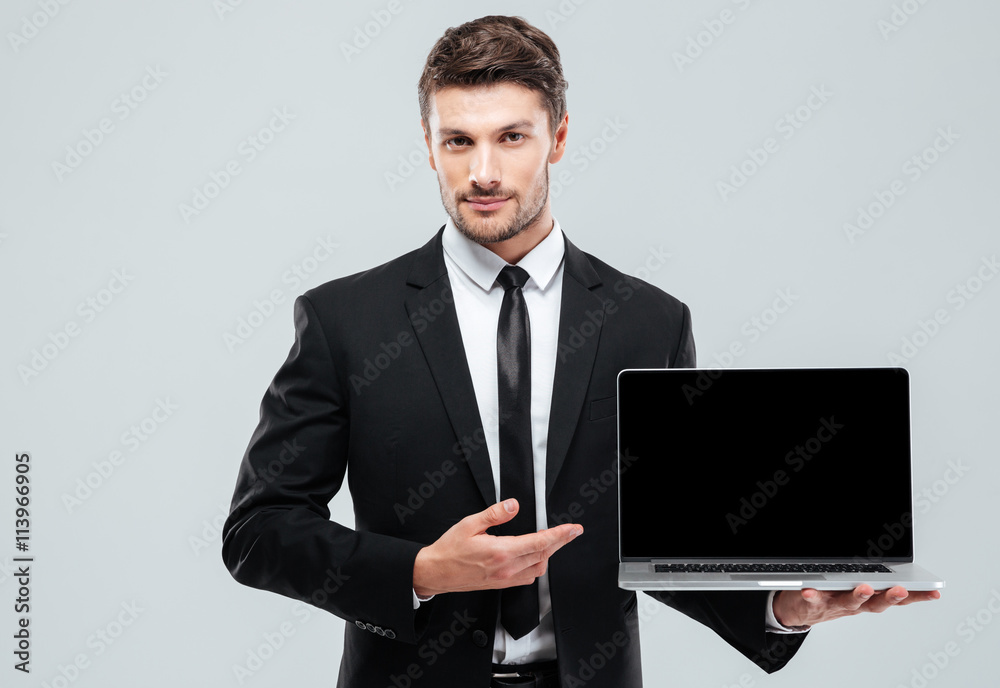 Handsome young businessman showing blank screen laptop Handsome young businessman showing blank screen laptop