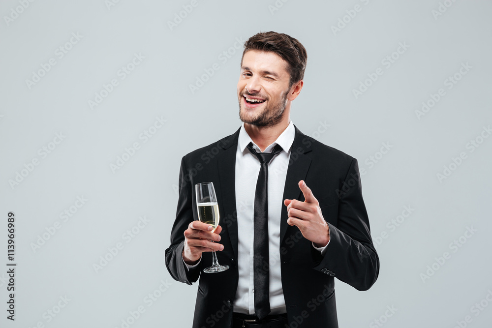 Happy handsome young businessman drinking champagne and pointing on you Happy handsome young businessman drinking champagne and pointing on you