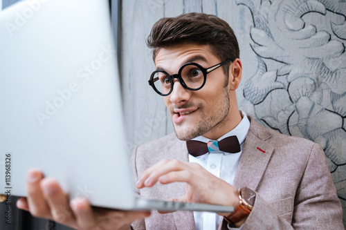 Nerd man holding laptop and making funny face