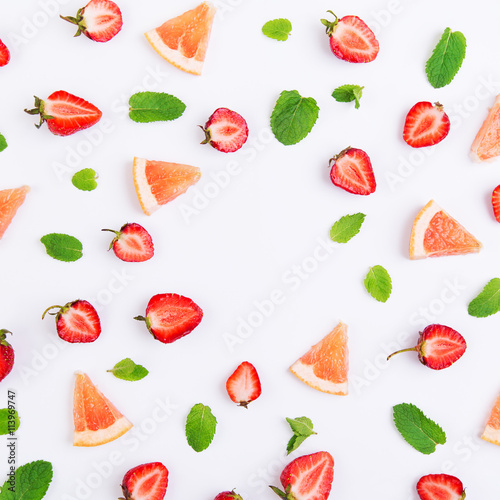 Fototapeta Naklejka Na Ścianę i Meble -  Colorful pattern of strawberry halves, slices of grapefruit and mint leaves on a white background. Top view with copyspace