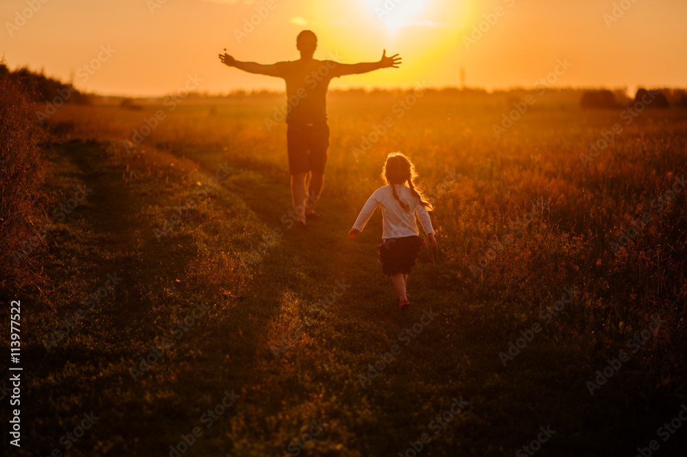 daughter running to father in the field at sunset,silhouette