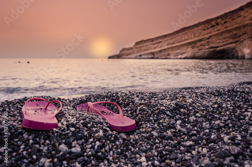 Sunset with woman's sandals on the beach 