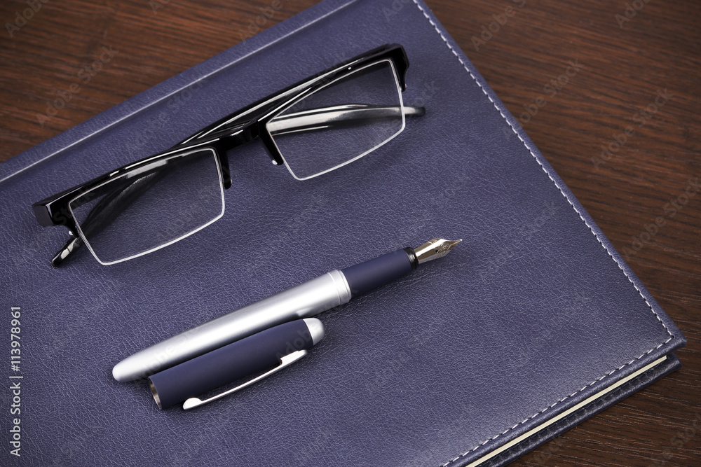 Business accessories on desktop: notebook, diary, fountain pen, cufflinks, glasses Business accessories on desktop: notebook, diary, fountain pen, cufflinks, glasses