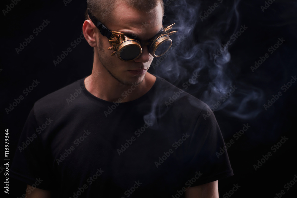 Portrait of man in crazy sunglasses. A man smoking cigare. Isolated on black background.