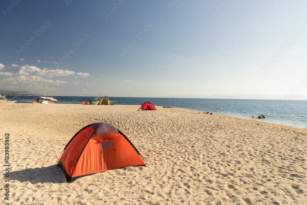 tents on beach of white sandunder blue sky