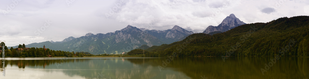 Lake in the German Alps with a chain of mountain peaks on the horizon. Reflection of the sky in water