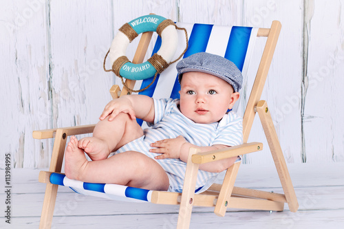 Funny little toddler sitting on the deckchair