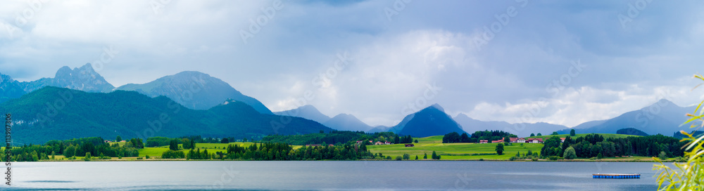 Lake in the German Alps with a chain of mountain peaks on the horizon. Reflection of the sky in water