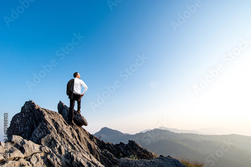businessman success hiking on the peak of rocks mountain at sunset, success winner, leader concept