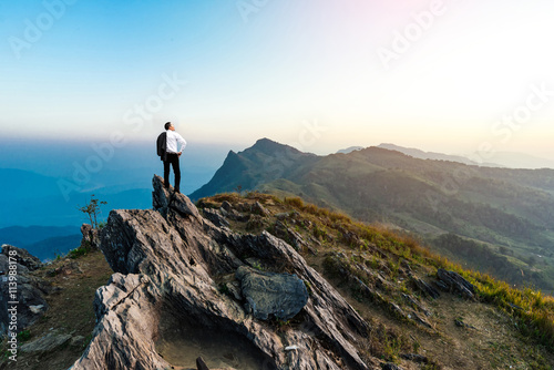 businessman success hiking on the peak of rocks mountain at sunset  success winner  leader concept