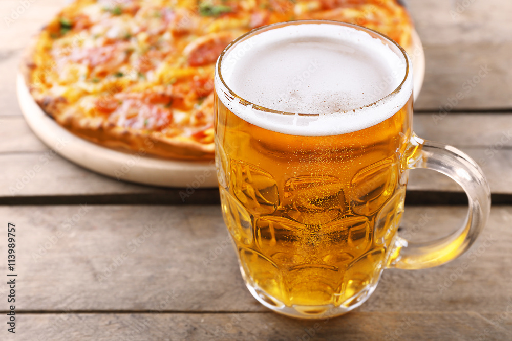 Tasty pizza and glass of beer are on wooden table, close up Tasty pizza and glass of beer are on wooden table, close up