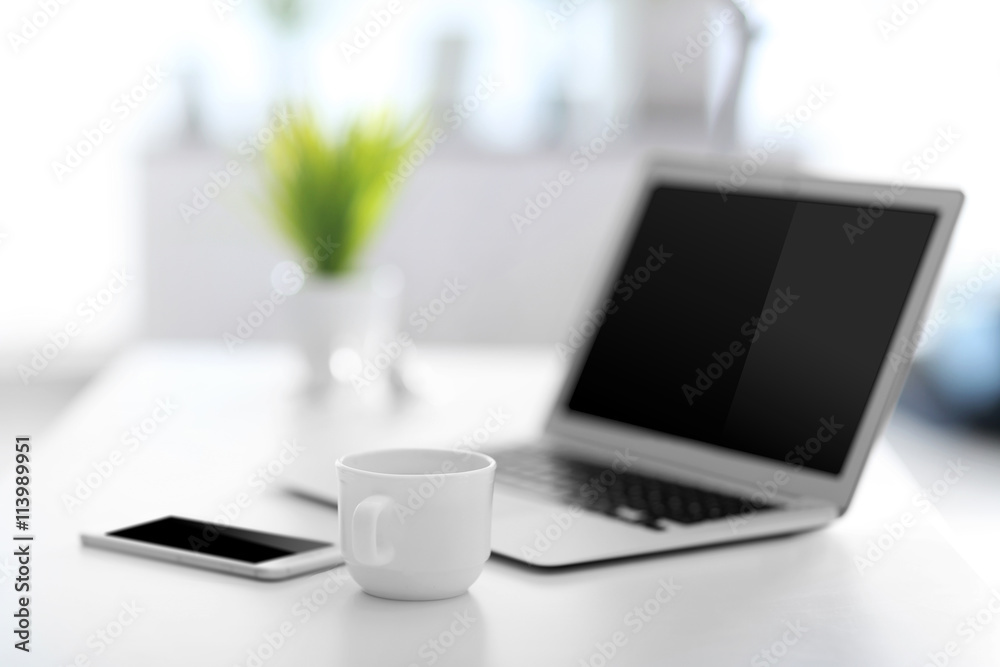 Workplace with laptop, mobile phone and cup of coffee indoors Workplace with laptop, mobile phone and cup of coffee indoors