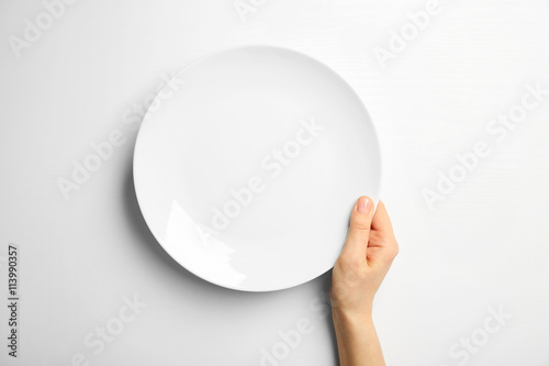 Female hand and empty plate isolated on white