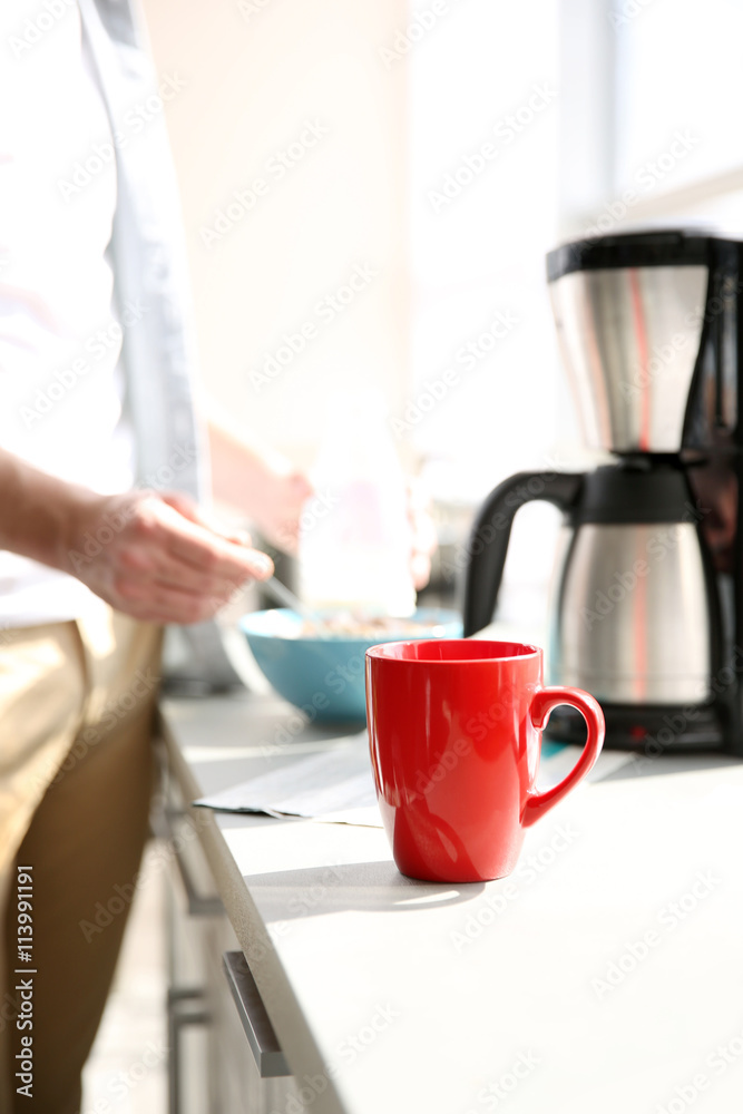 Red cup of coffee and young man on background Red cup of coffee and young man on background