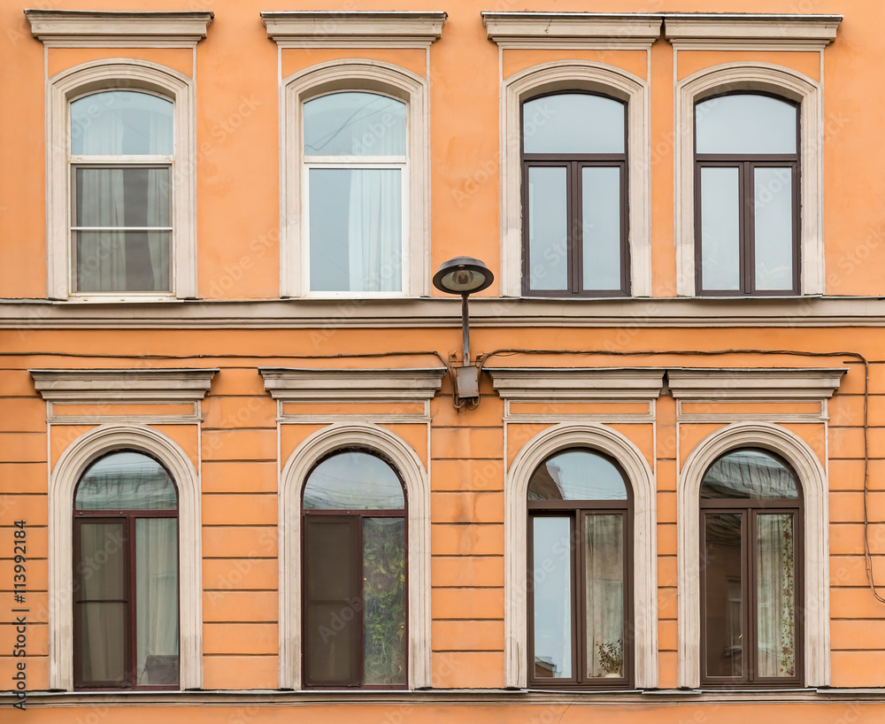 Several windows in a row and streetlight on facade of urban apartment building front view, St. Petersburg, Russia.