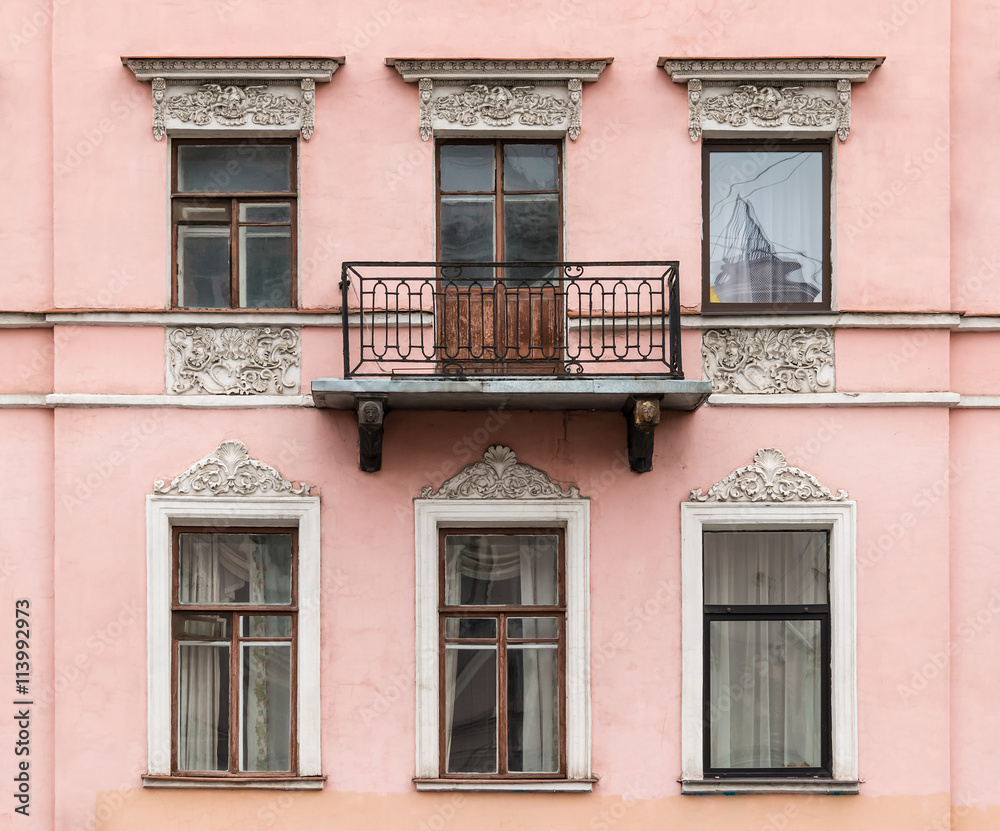 Several windows in a row and balcony on facade of urban apartment building front view, St. Petersburg, Russia.