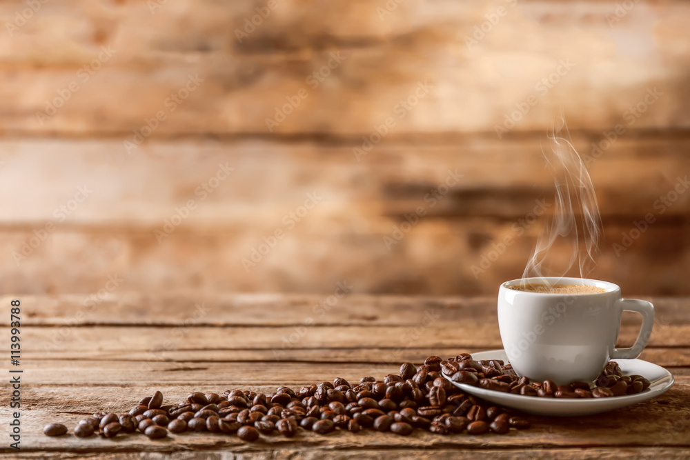 Cup of coffee with beans on wooden table - obrazy, fototapety, plakaty 