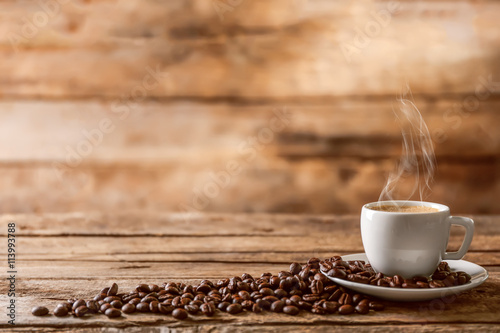 Fotografija Cup of coffee with beans on wooden table