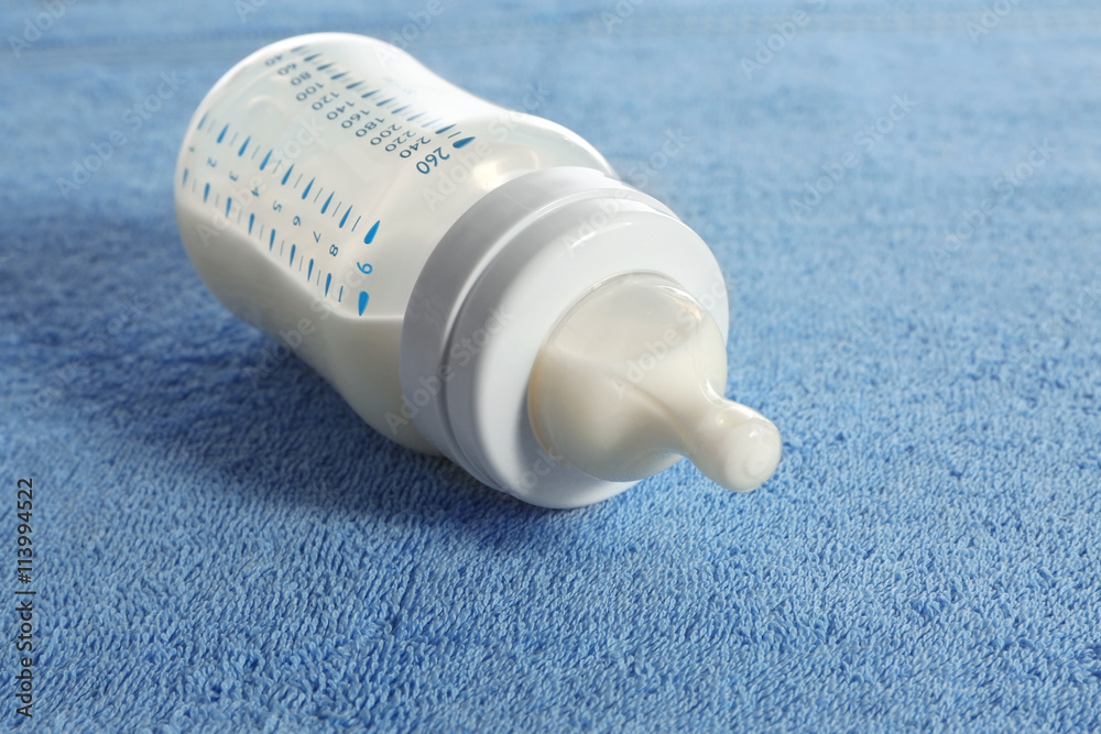 Baby bottle with milk on blue soft towel Baby bottle with milk on blue soft towel