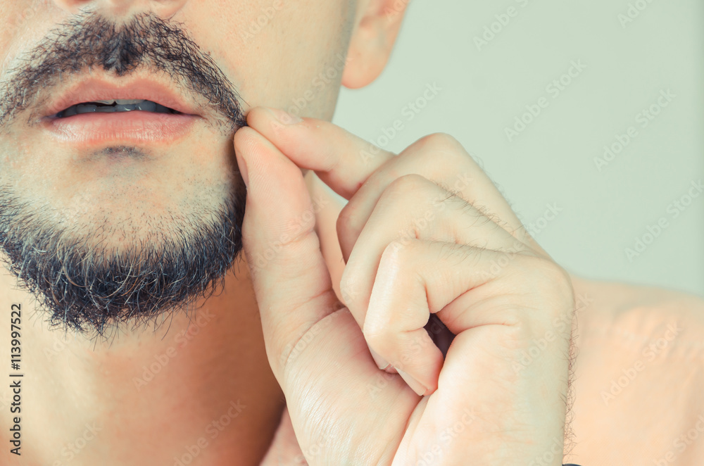 Fototapeta premium man with a beard and mustache shows and pulls the ends