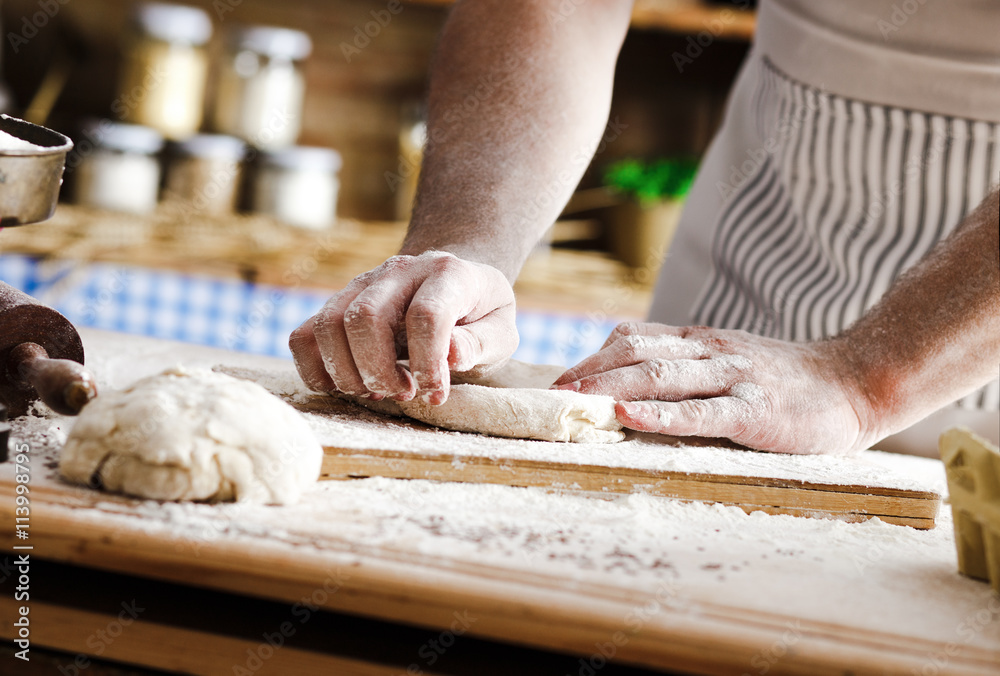 Close up of male baker hands kneading the dough with flour powder.