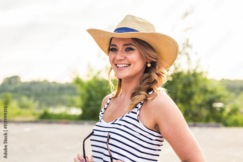 Portrait of pretty cheerful woman wearing straw hat in sunny warm weather day.
