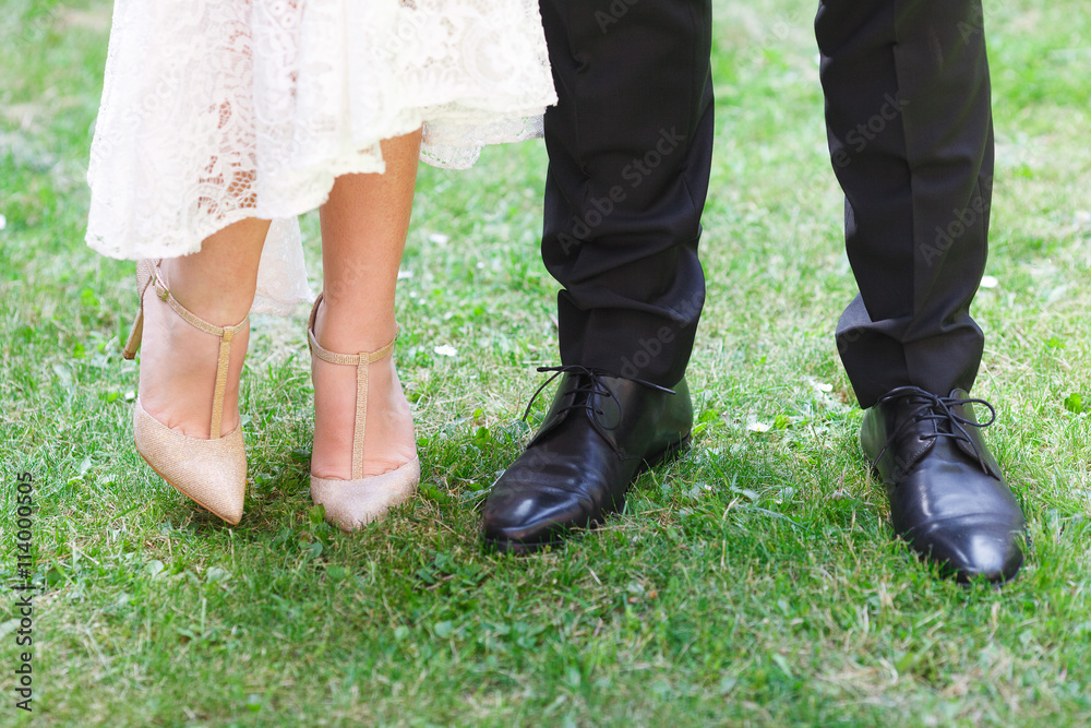 Close-up of bride's and groom's feet standing on green grass