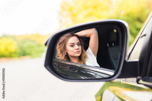 Young woman looking in the car mirror