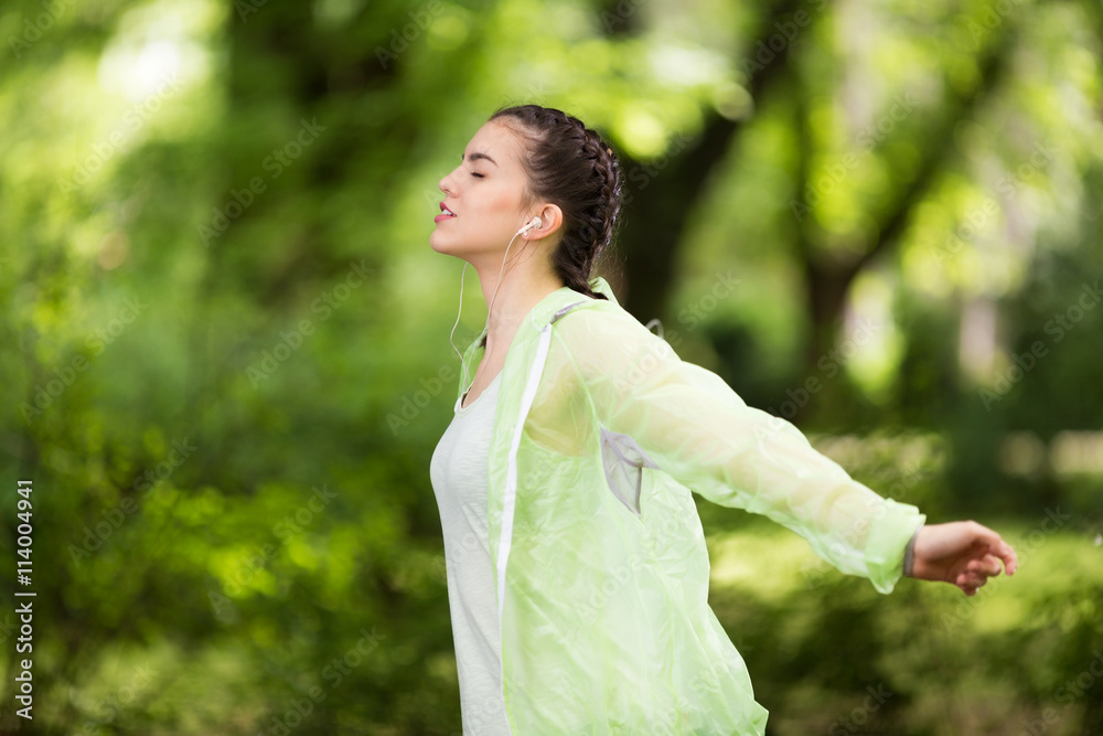 Young caucasian girl exercising in the park while listening to a music. Young caucasian girl exercising in the park while listening to a music.