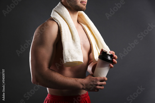 Young man with sports nutrition on dark background