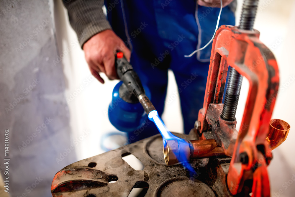 Φωτογραφία worker, plumber using blowtorch for soldering copper fittings