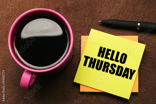 Hello Thursday - text on sticky note with a pen and cup of coffee