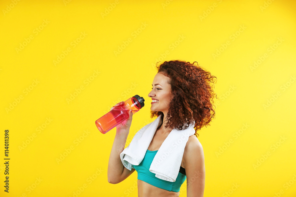 Attractive woman with bottle in hand on yellow background Attractive woman with bottle in hand on yellow background