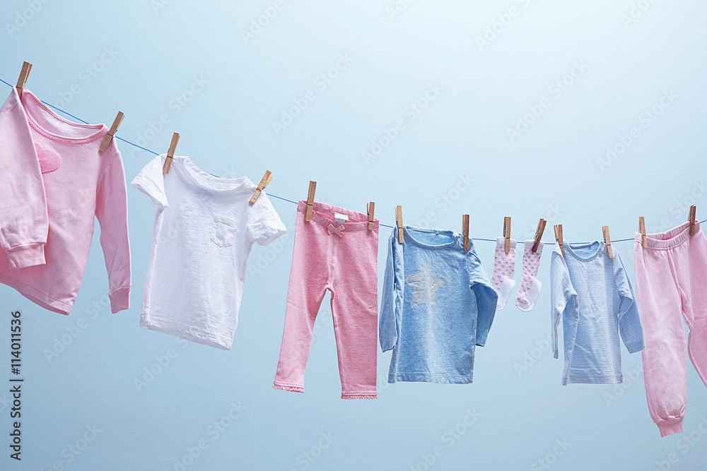 Baby clothes hanging on rope on grey background Baby clothes hanging on rope on grey background