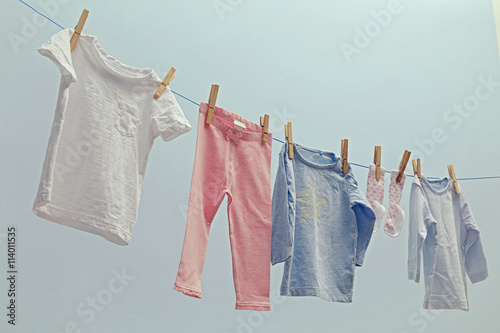 Baby clothes hanging on rope on grey background