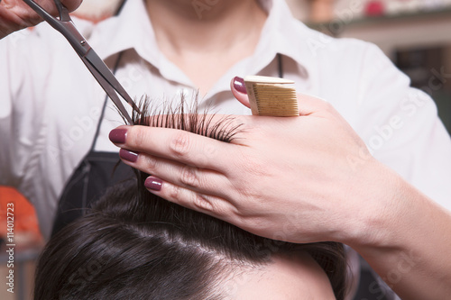 Cropped shot of female hairdresser cutting man's hair with scissors at hairdressing salon. Getting rid of those split ends.