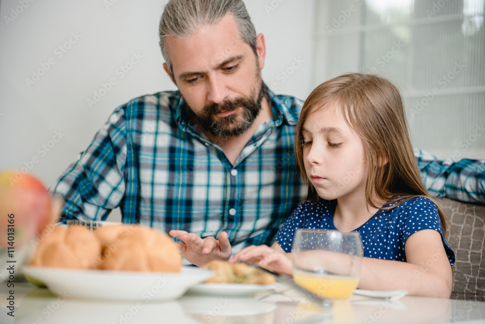 Father and daughter using tablet during breakfast