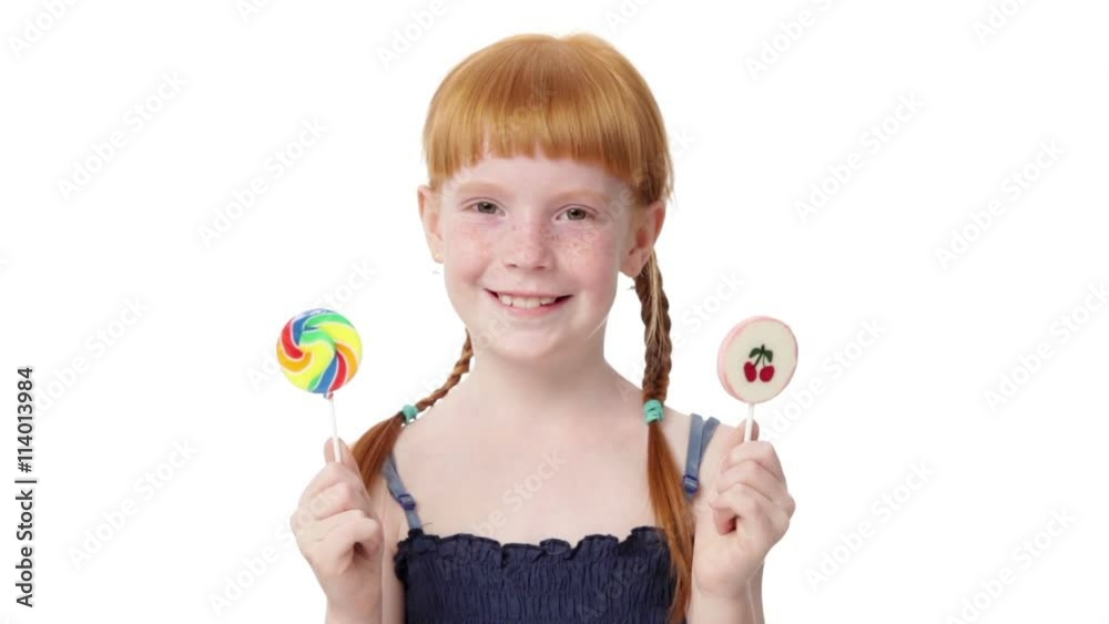 Little redhead girl is holding two lollypops in both hands, smiling, isolated on white background Little redhead girl is holding two lollypops in both hands, smiling, isolated on white background