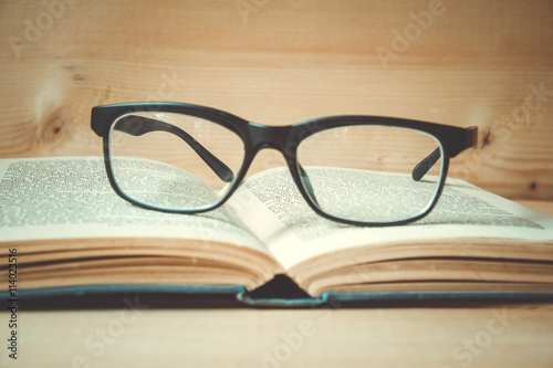 Old books and glasses on a wooden table with filter effect retro