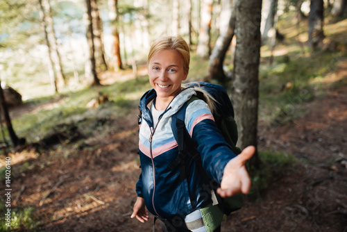 Shot of a beautiful young woman offering you a hand while hiking