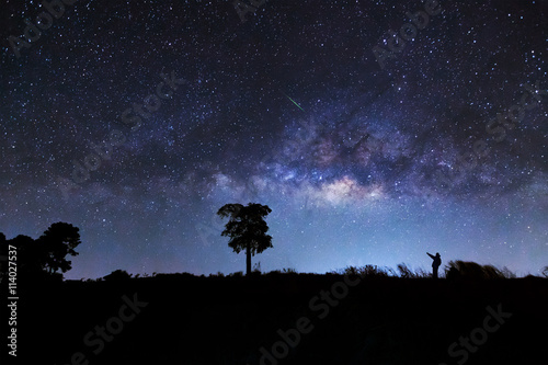A man pointed to a meteor and milky way galaxy on a night sky, L
